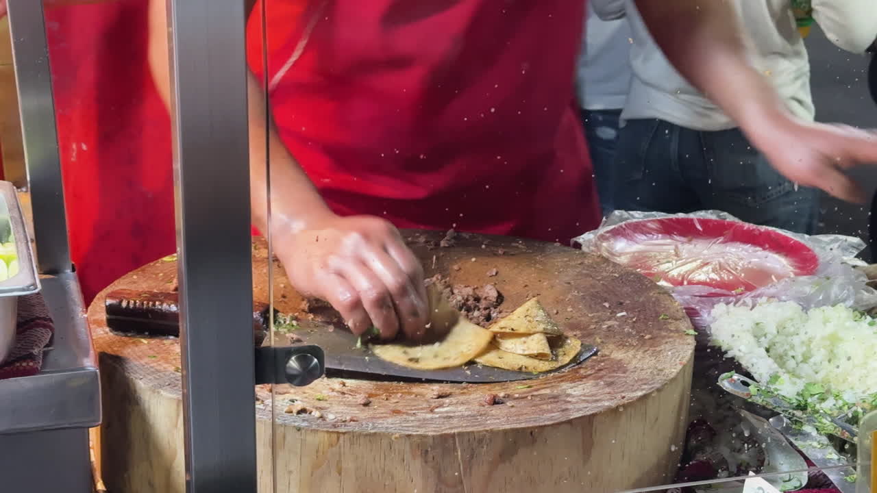 Vendedor ambulante prepara tacos de suadero y longaniza, ambiente animado.