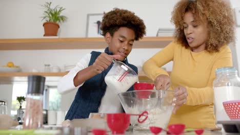 happy african american mother and son baking in kitchen, slow motion