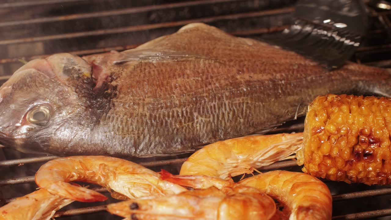 Chef cooking red salmon fish steaks with oil and spices on grill close-up. Prawns on fire throwing them on pan. Making Dorado fishes on frying grill. Restaurant Food concept. Sea food barbecue.