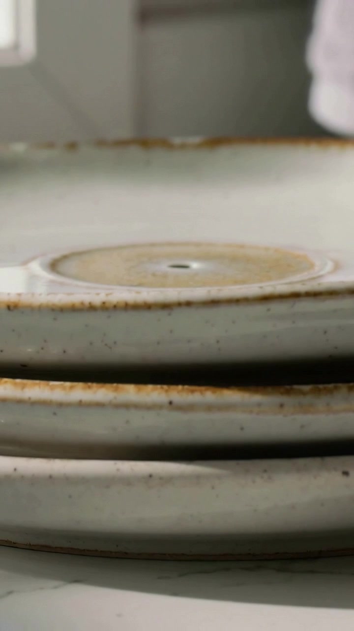 Video verticale: Telecamera che si sposta mostrando piatti di ceramica sul bancone, rivelando un segno rotondo e bordi marroni