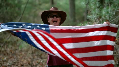 Zeitlupe-Einer-Frau-Mit-Cowboyhut-Und-Flagge,-Die-Lächelnd-Und-Lachend-Eine-Flagge-Herumpeitscht