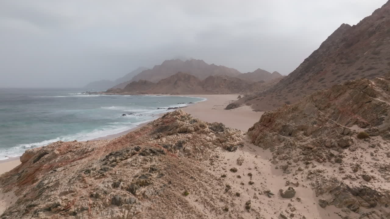 Strada costiera e terreno roccioso lungo la spiaggia dell'Oman, vista panoramica sull'oceano con montagne