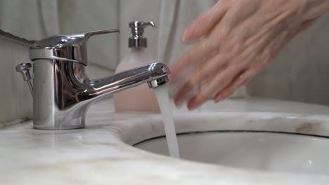 Las-Manos-De-La-Anciana-Se-Lavan-Con-Agua-Del-Grifo-Con-Jabón-Líquido,-Luego-Se-Enjuagan-Y-Se-Limpian-Con-Una-Toalla-De-Tela-Blanca---Vista-Lateral-De-Primer-Plano-Estático-4k