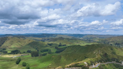 aerial flies above the first saddle of new zealand's famous forgotten world highway with views across the rich green pastures of taranaki farms and hilly landscape