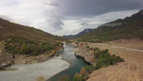 aerial flight over a bridge with a human standing over vjose river in southern albania during a summer vacation road trip