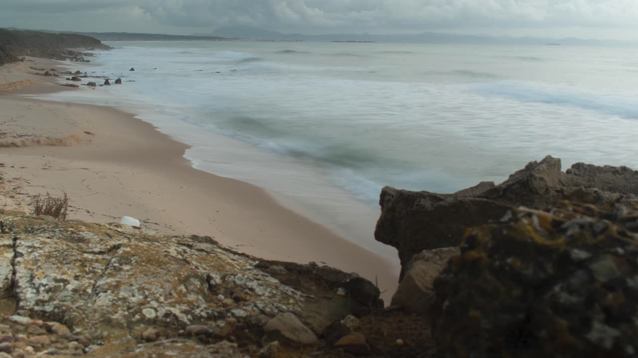 스페인의 외딴 모래 해변을 때리는 거품 파도의 시간 경과