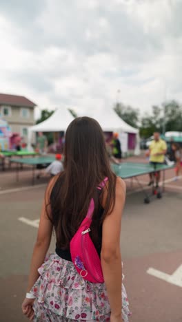 woman walking at a festival with table tennis in the background