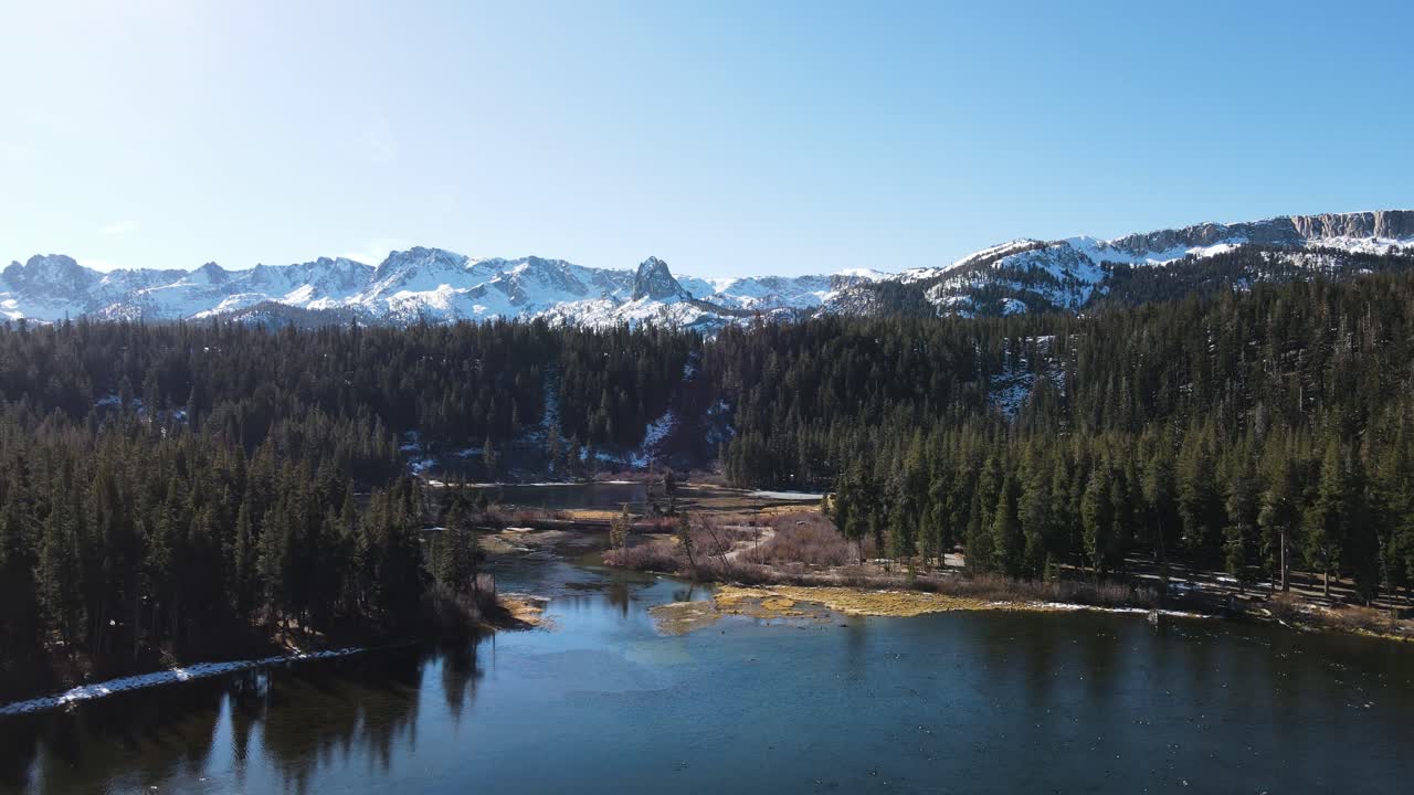 drone volando hacia montañas nevadas sobre lagos alpinos en mammoth lakes california