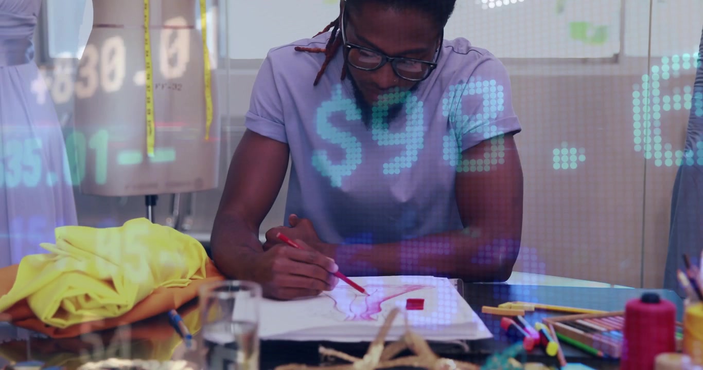 Male fashion designer leaning at worktable, drawing red strokes while numeric graphics guiding work