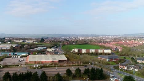 Seguimiento-Aéreo-De-Izquierda-A-Derecha-Mirando-A-Través-Del-Borde-De-La-Zona-Comercial-De-Sowton-Y,-En-La-Distancia,-El-Centro-De-La-Ciudad-De-Exeter