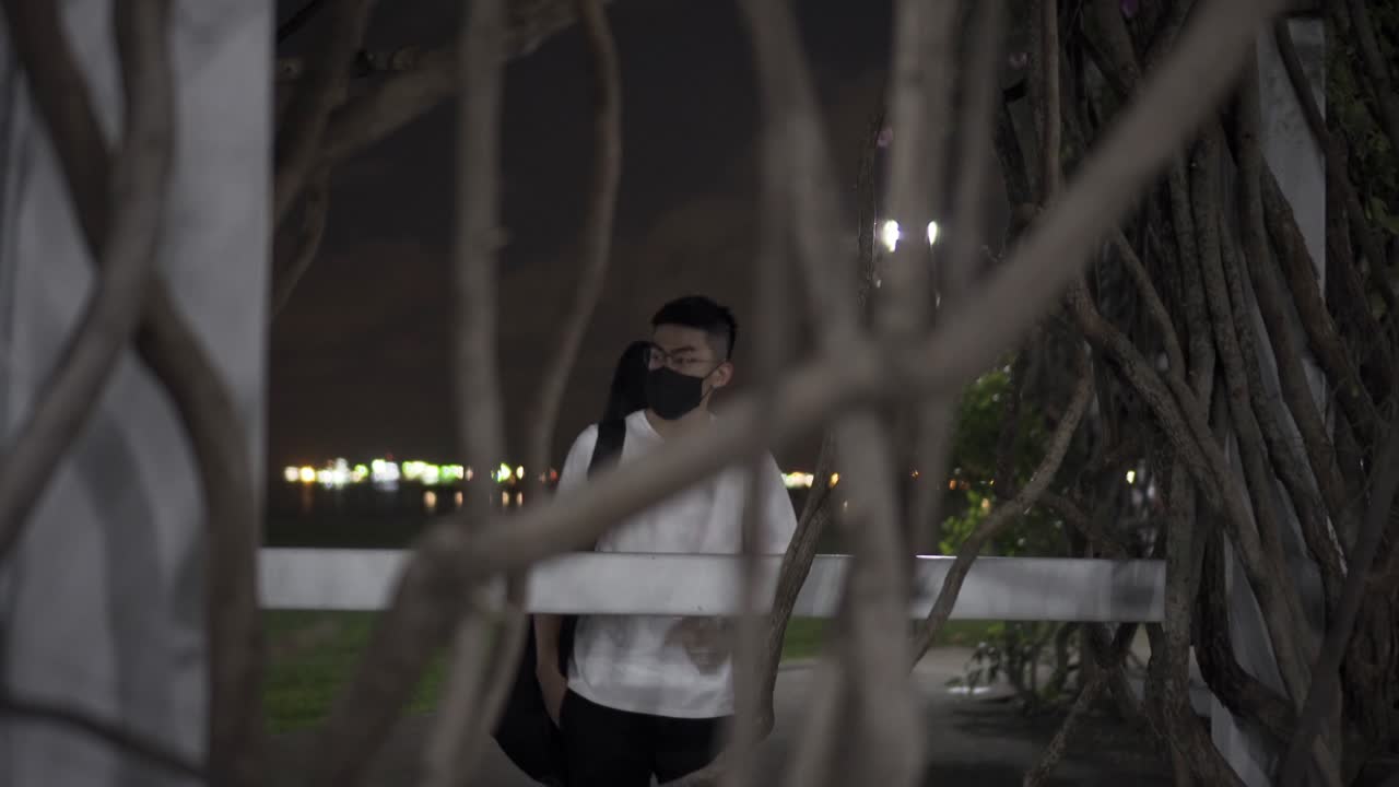 코로나 바이러스 동안 기타를 들고 검은 마스크를 쓴 남자의 나뭇가지를 가로질러 보기