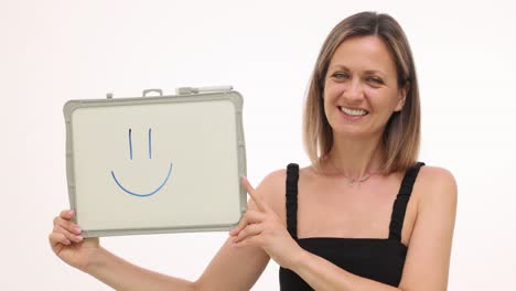 smiling woman holding a whiteboard with a hand-drawn smiley face
