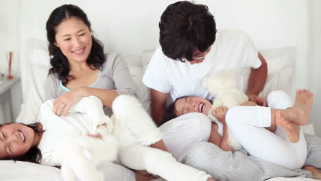 parents playing with their daughter and teddy bears