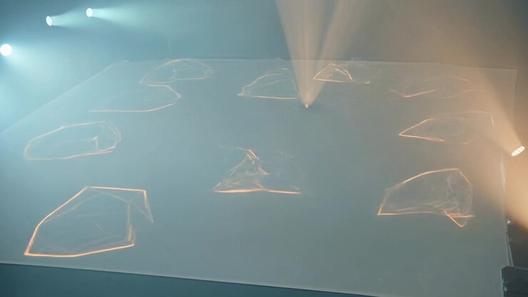 Cueing stage lights casting shifting polygons on scrim with haze for stage effect