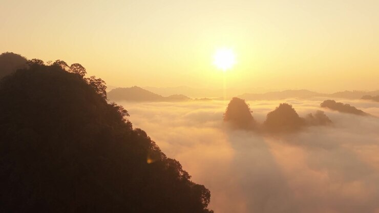 Vista aérea del amanecer sobre picos montañosos cubiertos de niebla