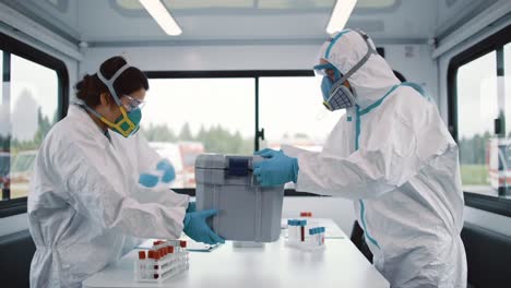medical response team in protective gear handling samples and equipment inside a mobile laboratory in an emergency situation