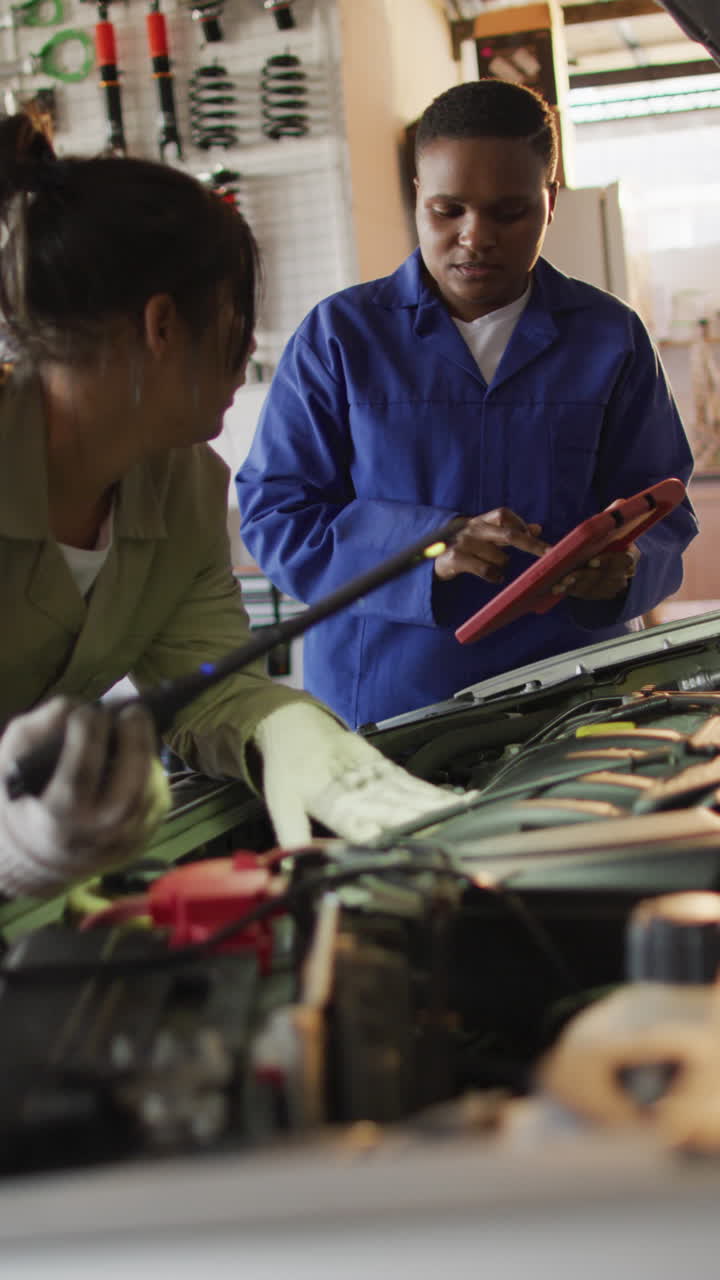video vertical de dos mecánicas de automóviles femeninas diversas comprobando el coche