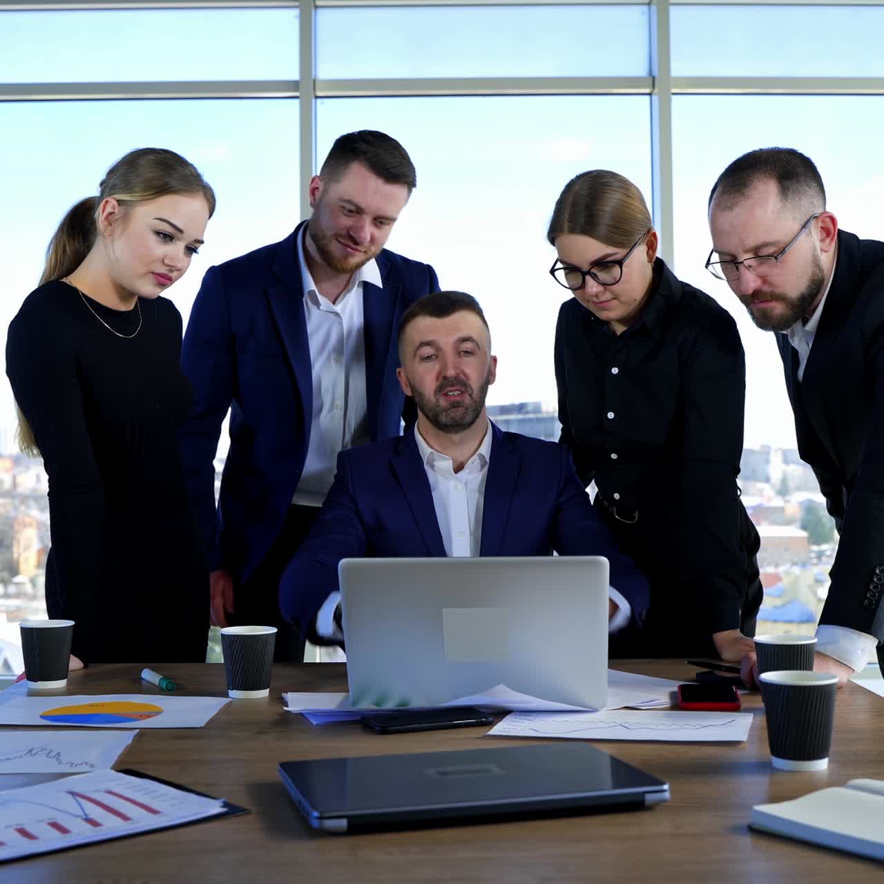Teamwork of business partners in office. Group of young people in elegant clothes looking into a laptop and discuss business plan together