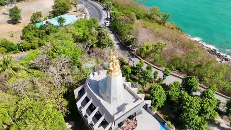 drone footage captures the scenic promthep cape lighthouse in phuket, thailand, surrounded by lush greenery and turquoise waters