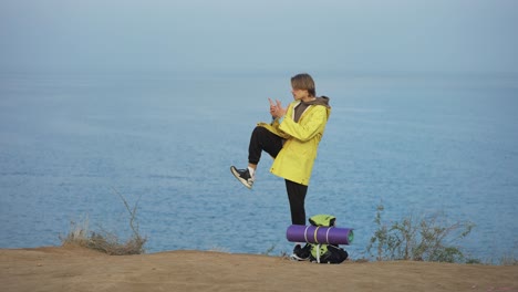 young traveller standing on the edge of the hill in front the sea and performing qigong