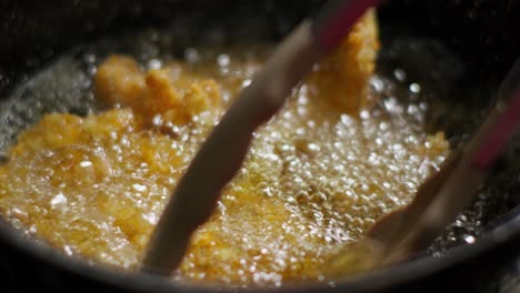 frying breaded chicken fillets in oil in a frying pan