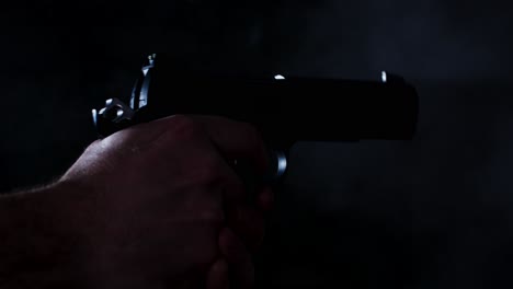 primer plano cinematográfico de una pistola que se dispara varias veces hasta que se vacía en una habitación oscura