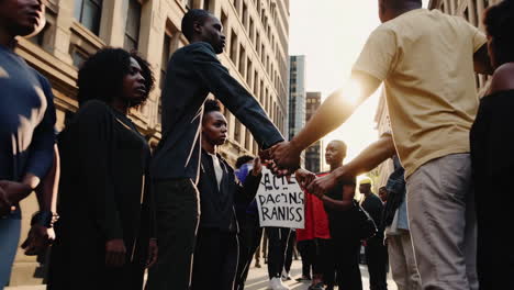 people holding hands in solidarity at a social justice demonstration