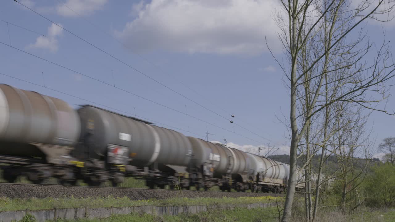 coches de tren acelerando a través de un paisaje rural bajo un cielo azul claro, capturando la esencia del transporte