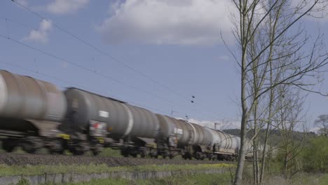 Vagones-De-Tren-Acelerando-A-Través-De-Un-Paisaje-Rural-Bajo-Un-Cielo-Azul-Claro,-Capturando-La-Esencia-Del-Transporte