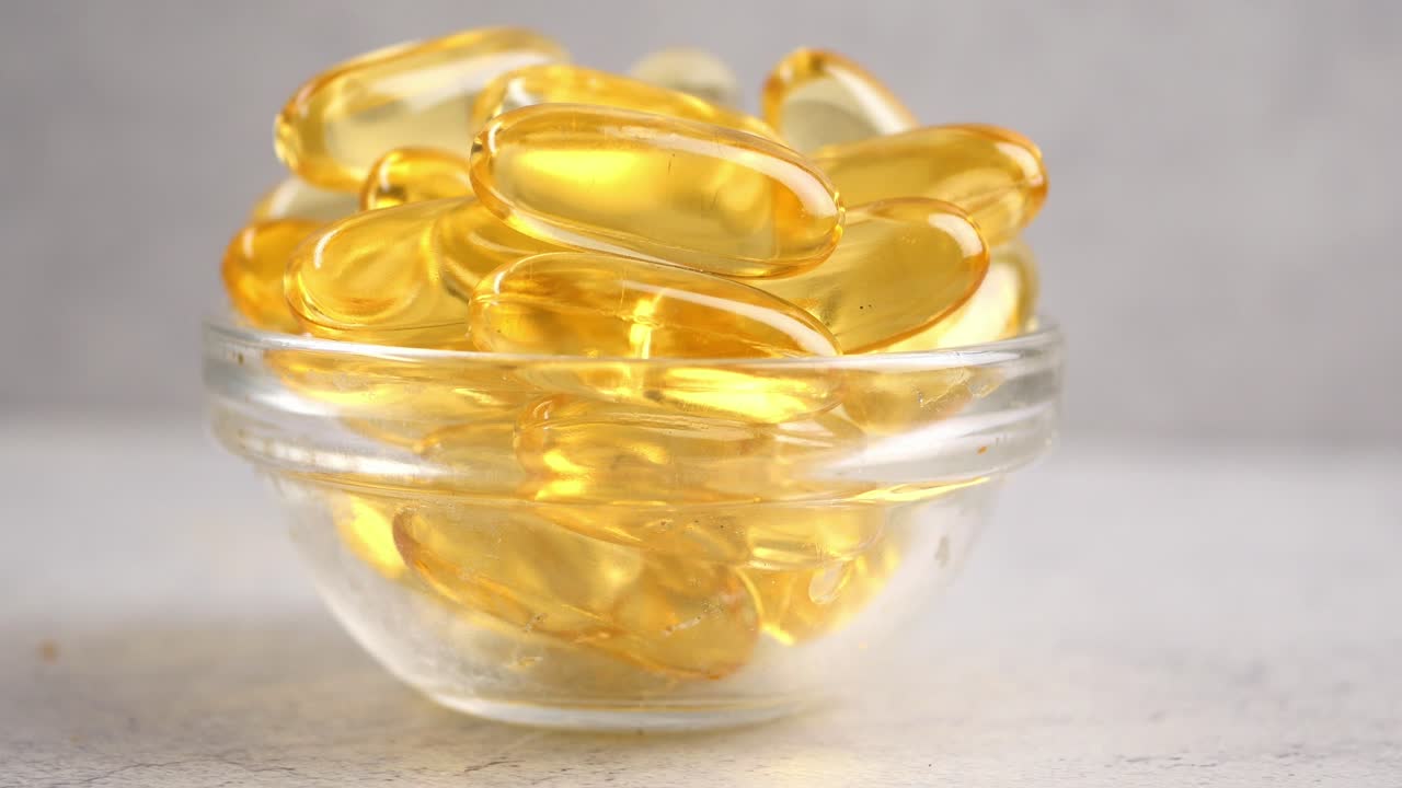 Foto close-up Kapsul Minyak Ikan Omega-3 Kuning dalam Mangkuk Kaca