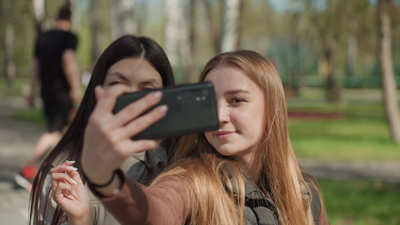 야외에서 웃는 친구, 자연 속 친구들의 모습, 푸르른 녹음 속에서 따뜻한 순간을 나누는 여성들, 햇빛 아래 야외에서 진정한 친목을 보여주는 두 여성을 담은 편안한 사진