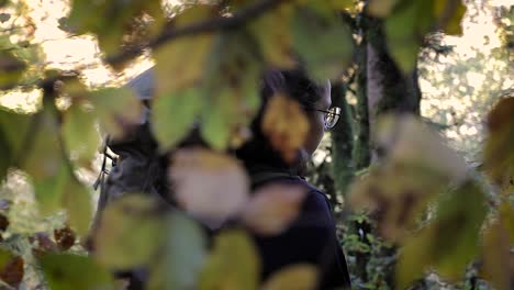 slow motion, millennial girl backpacker hiking outdoors. camera behind leaves