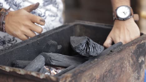 Starting-a-fire-with-a-lighter,-newspaper-and-charcoal-on-a-old-bbq-pit