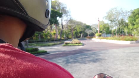 slow motion driving scooter in bali indonesia with amazing sunlight on helmet and tropical nature. beautiful white man driving scooter on modern road in nusa dua.