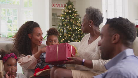 multi-generation family celebrating christmas at home opening presents together