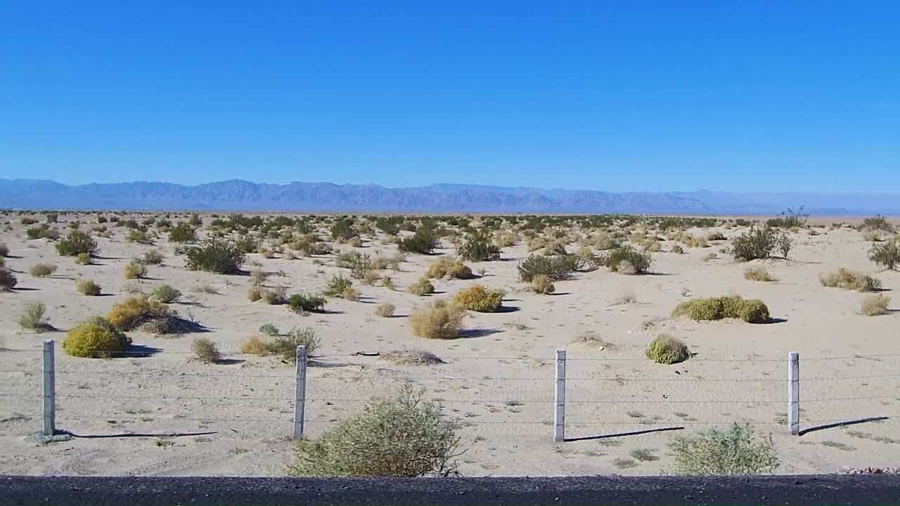 vista desde la ventana del copiloto del camión que muestra la tierra y las montañas en el fondo mientras se conduce por la carretera