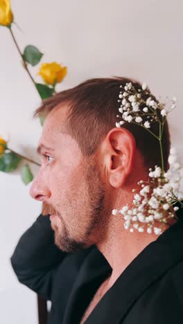 hombre en blazer negro con rosas amarillas y flores blancas