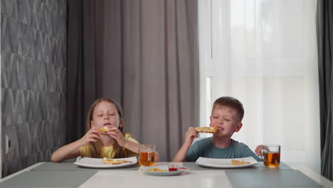 kids sitting at dining table enjoying grilled egg pizza with berry juice in glass cups under bright indoor setting with cozy curtains and patterned wall background