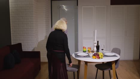 senior retired couple having fun during romantic supper in the kitchen celebrating their anniversary