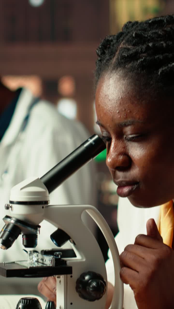 Scienziata afroamericana che usa un microscopio in laboratorio