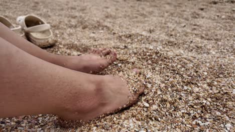 Bare feet are submerged in the sand at Karadag beach in Crimea, Russia