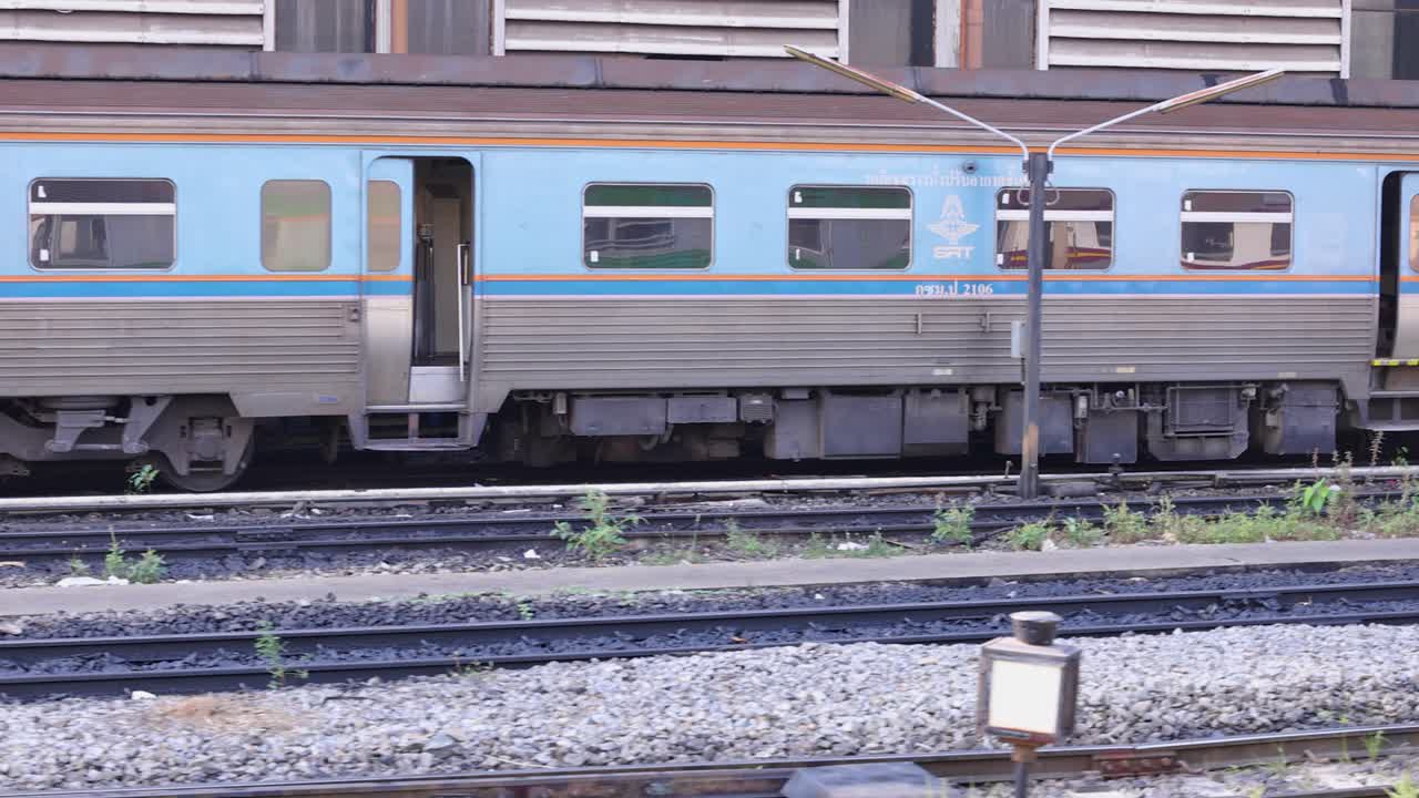 Un vivace motore diesel traina un treno passeggeri lungo i binari di Bangkok durante il giorno