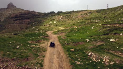 drone following off-road buggy driving on uphill dirt road leading to aqoura lakes in lebanon