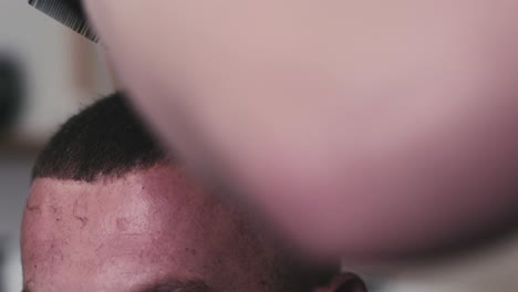 peluquero cortando el cabello de una persona que usa podadoras eléctricas y un peine en un estudio de cabello