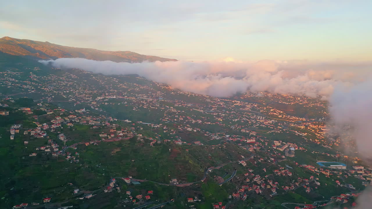 Aerial view village mist on sunset. fog rolling green island hillside