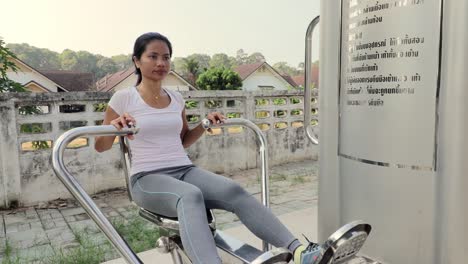 a beautiful woman doing chest workout in an outdoor gym in thailand - mid shot