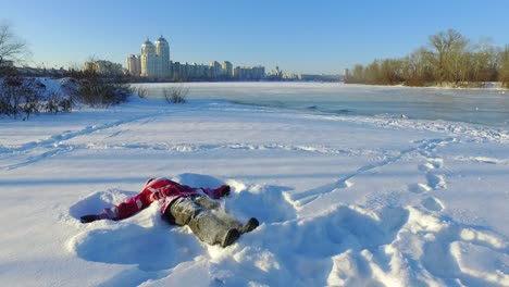 happy little girl lying on snow in city park. snow playing. happy winter holiday