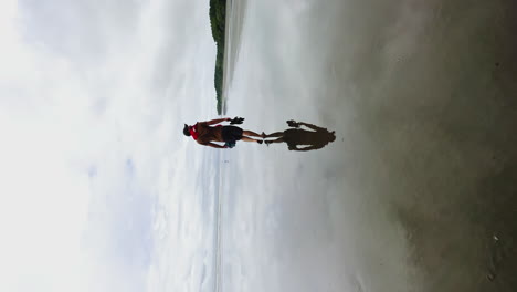 whale tale national park, costa rica, vertical shot, caucasian male walking on flat water with stunning reflection