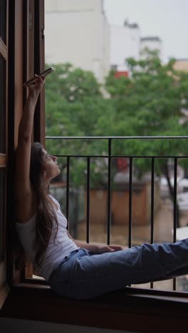 woman taking a selfie or video call on a rainy day from a balcony