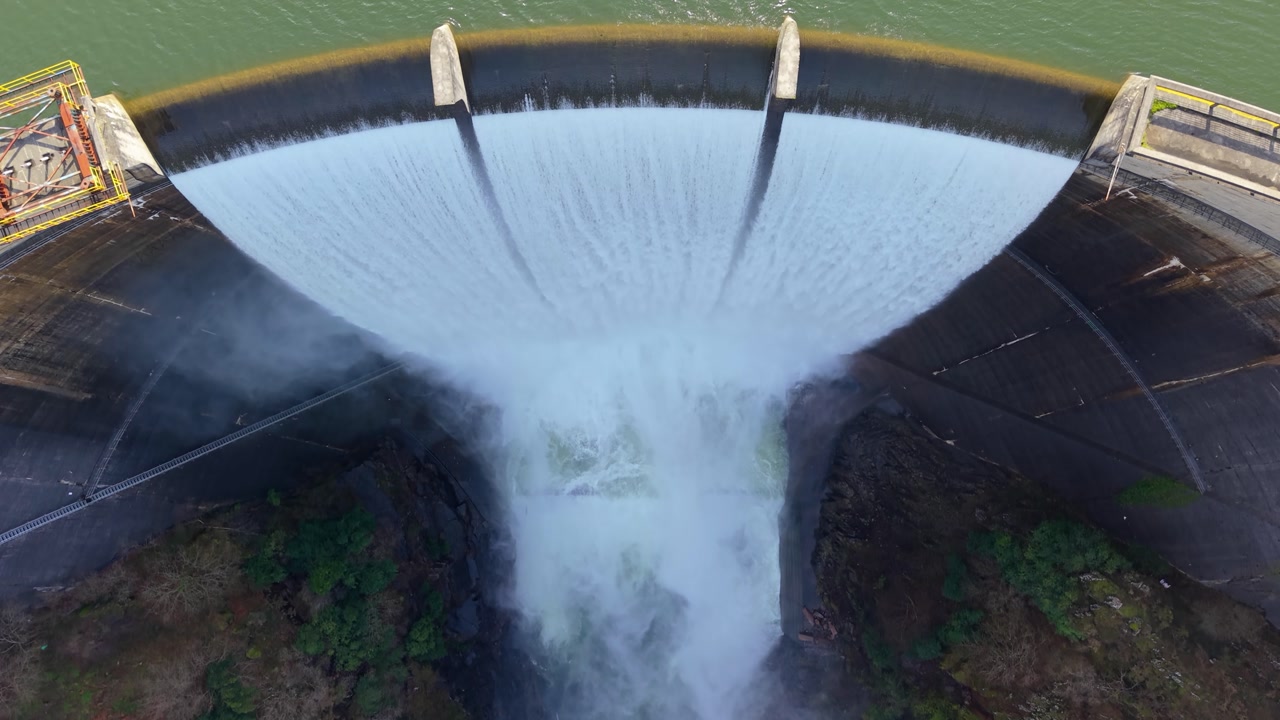 Topdown View Of Water Cascading From Curved Concrete Spillway Of Eume Reservoir In Galicia, Spain. aerial shot